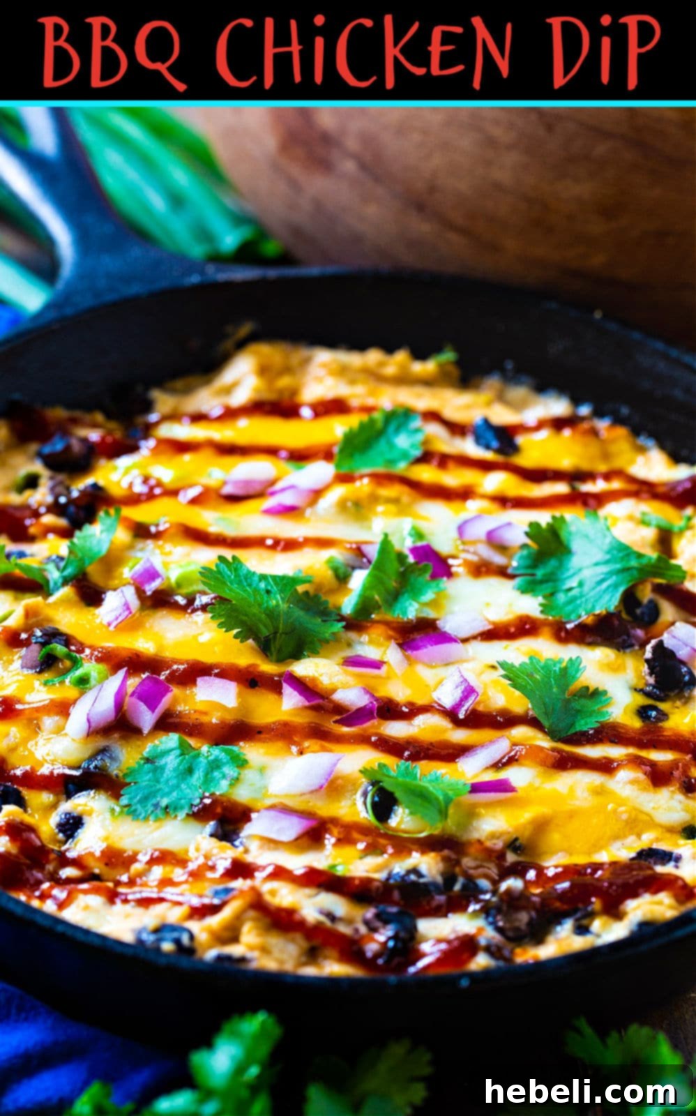 Ultimate BBQ Chicken Dip 6 A hand dipping a crispy tortilla chip into a skillet of warm, creamy BBQ Chicken Dip, showcasing its rich texture and deliciousness.