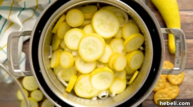 Steaming sliced yellow squash and onion in a pot.