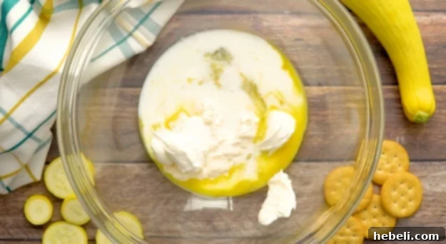 A bowl with mayonnaise, sour cream, egg, and milk being whisked together.