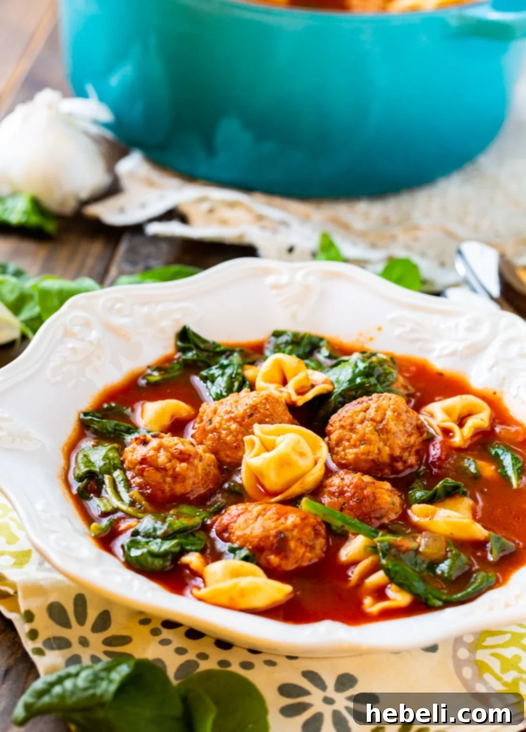 A single serving of Meatball and Tortellini Soup presented beautifully in a white bowl.