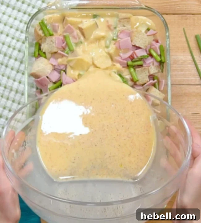 Pouring the egg mixture over the casserole before refrigeration.