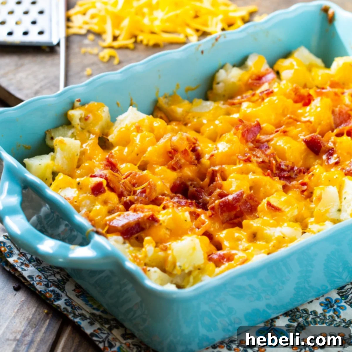 A vibrant blue baking dish filled with golden-brown Cheesy Bacon Ranch Potatoes, topped with melted cheese and crumbled bacon.