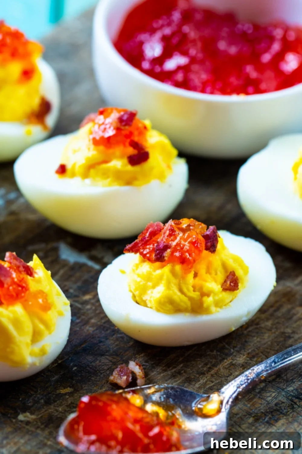 Smoky Bacon & Sweet Heat Deviled Eggs 4 A vibrant platter of Red Pepper Jelly Deviled Eggs with Bacon, accompanied by a small bowl of the glistening pepper jelly.