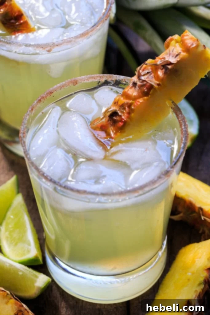 Two Pineapple-Cinnamon Margaritas garnished with pineapple and cinnamon