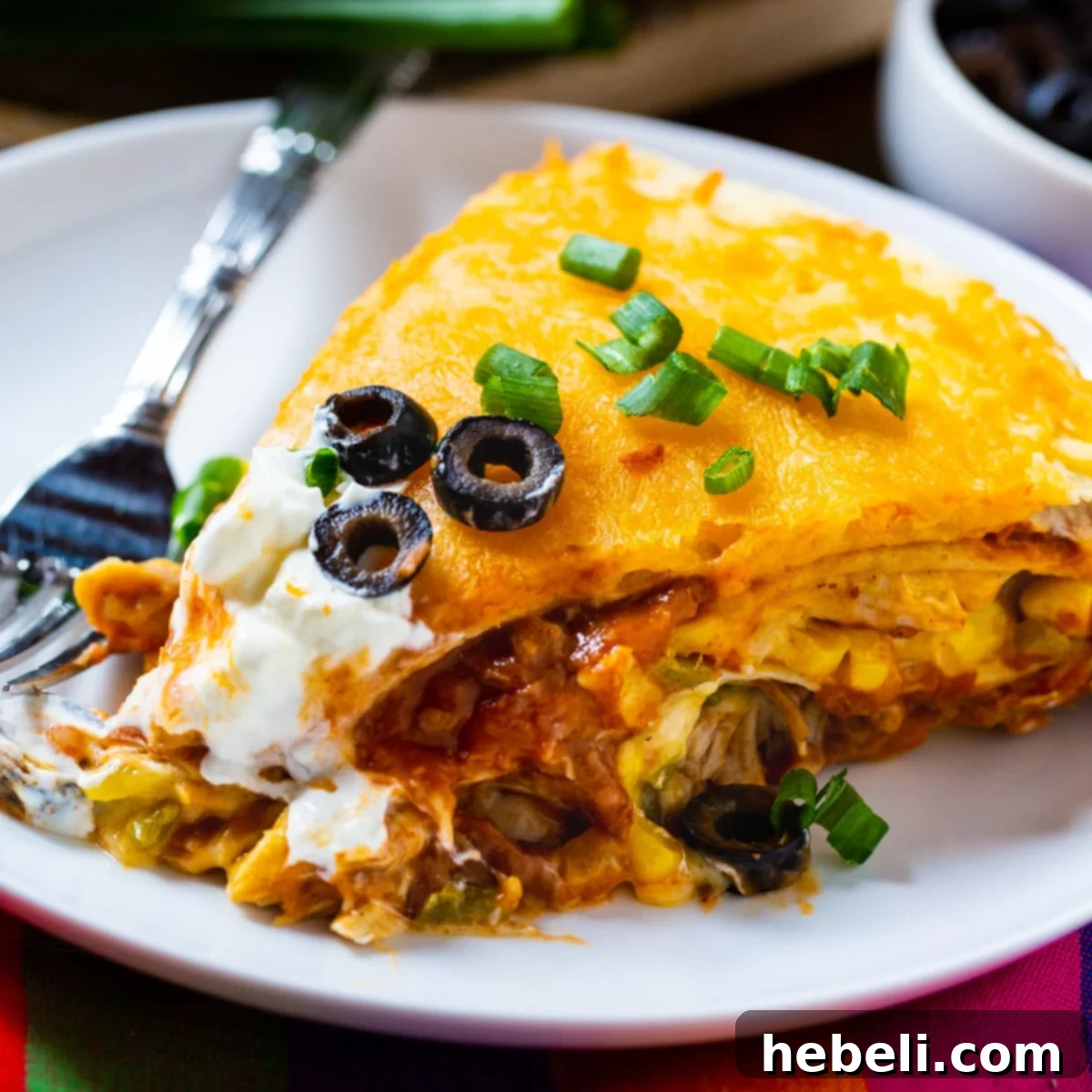 A perfectly portioned slice of One Pot Chicken Tortilla Pie on a white plate, showcasing its rich layers of chicken, beans, and melted cheese.
