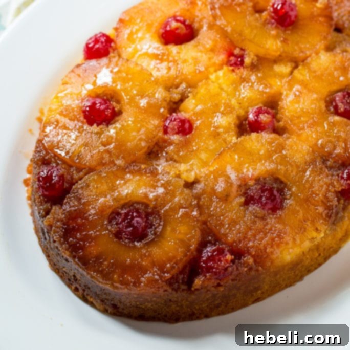 Golden Slow Cooker Pineapple Upside Down Cake with bright red cherries on a white platter