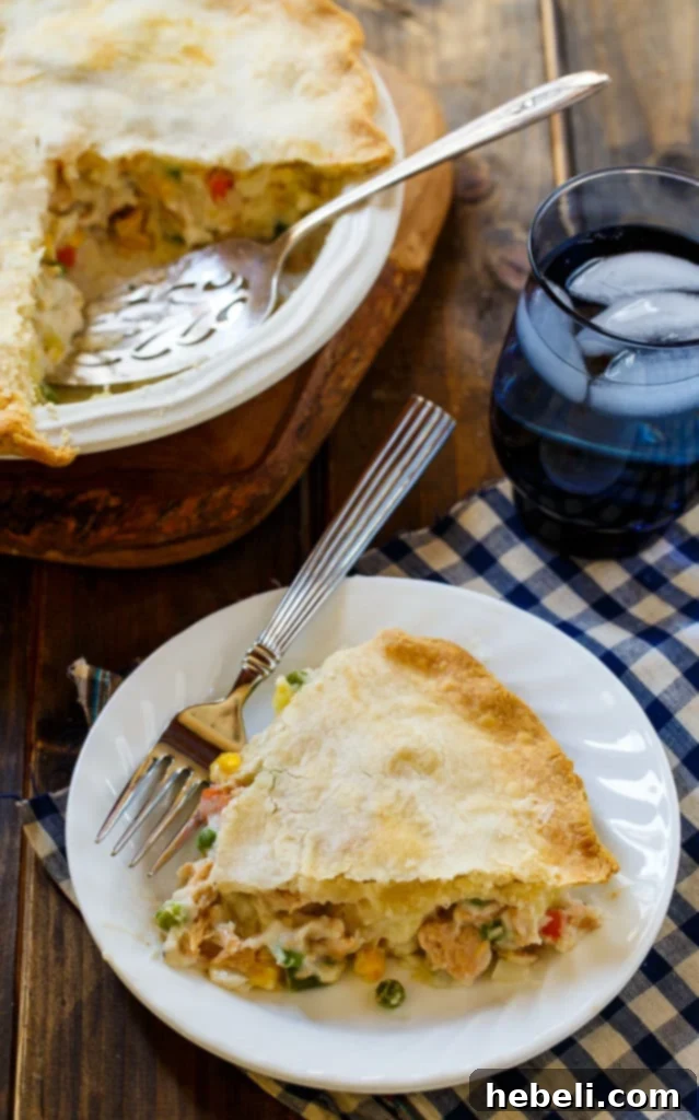A close-up view of a baked Salmon Pot Pie, showing the perfectly browned, crimped edges of the pie crust and a glimpse of the creamy filling inside.
