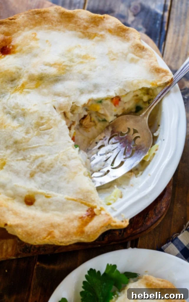 A serving of Salmon Pot Pie on a plate, with a fork ready to enjoy. The golden crust is visible, and the rich filling of salmon and vegetables is enticing.