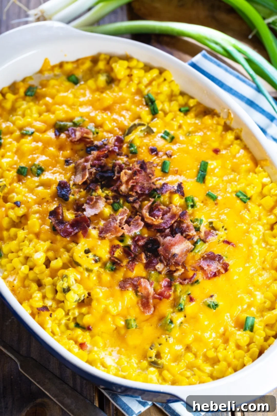 Cooked corn casserole topped with crumbled bacon in casserole dish. Ready to serve.