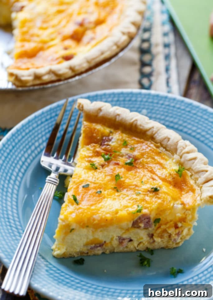 A beautiful slice of Easy Ham and Cheese Quiche on a blue plate, ready to be eaten