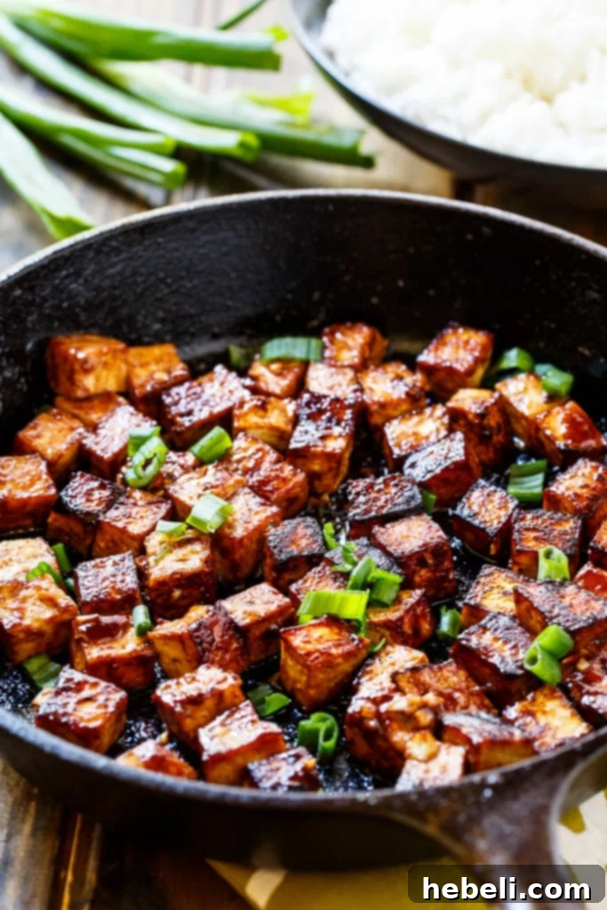 Tofu cubes marinating in a vibrant Asian garlic sauce, absorbing all the sweet, spicy, and savory flavors.
