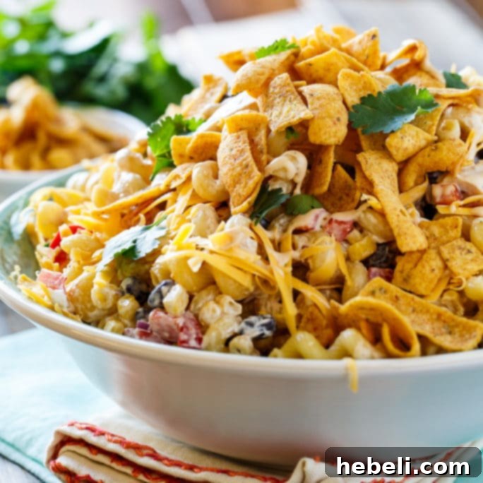 Zesty BBQ Ranch Pasta Toss 2 A large bowl of vibrant BBQ Ranch Pasta Salad, generously mixed with tender chicken pieces, corn, and black beans, garnished with fresh cilantro and crunchy corn chips.