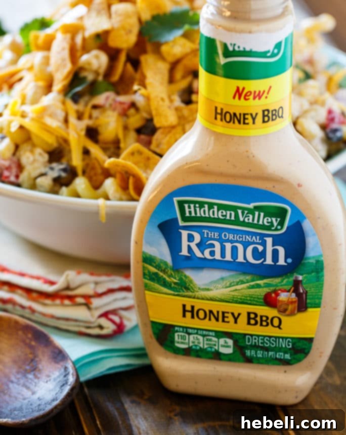 Zesty BBQ Ranch Pasta Toss 6 Close-up shot of the Hidden Valley Ranch Honey BBQ dressing bottle, highlighting its label, alongside a serving of the finished BBQ Ranch Pasta Salad, emphasizing the product's role.