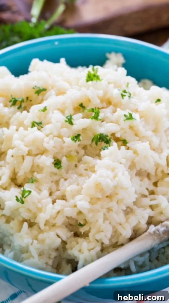 Close-up of golden, cooked long-grain rice with visible specks of Parmesan cheese and herbs.