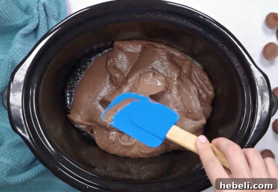 Spreading chocolate peanut butter cake batter evenly in a slow cooker.
