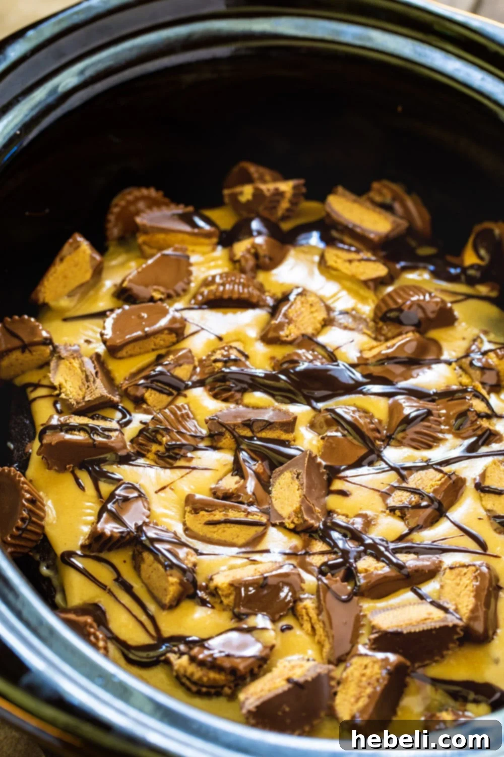 Delicious Slow Cooker Chocolate Peanut Butter Cake generously topped with peanut butter frosting and chopped peanut butter cups.