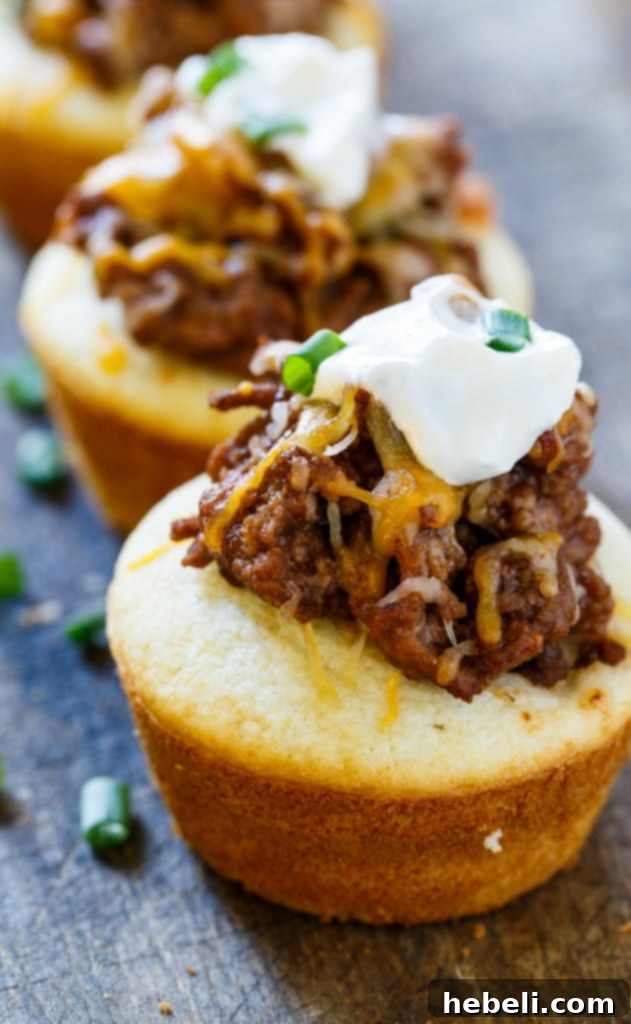 Stuffed Sloppy Joe Cornbread Muffins 6 Muffin tin with baked muffins topped with sloppy joe and cheese