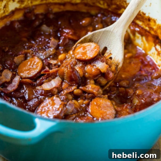 Delicious baked beans with smoked sausage and bacon, a hearty and flavorful dish, served in a rustic bowl.