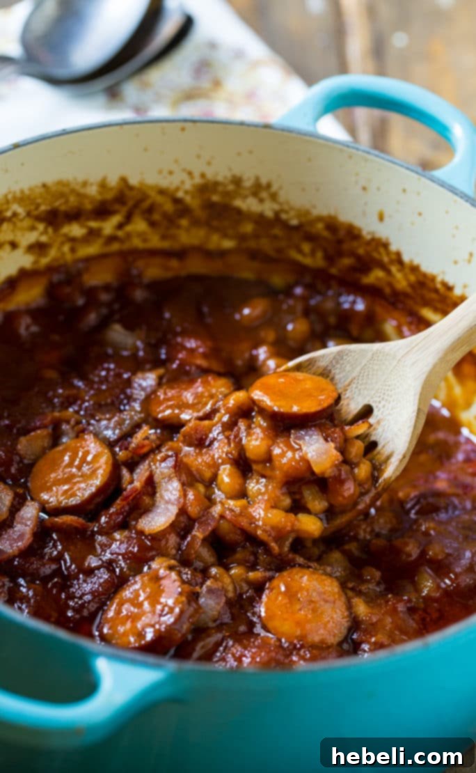 Oven-baked beans bubbling and thickening in an uncovered Dutch oven, showing the rich, caramelized surface.
