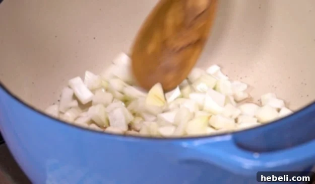 Cooking the chopped onion in rendered bacon grease until soft and translucent, stirring gently.
