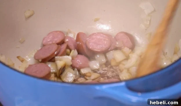 Browning sliced smoked sausage and fragrant chopped garlic in the Dutch oven with onions.