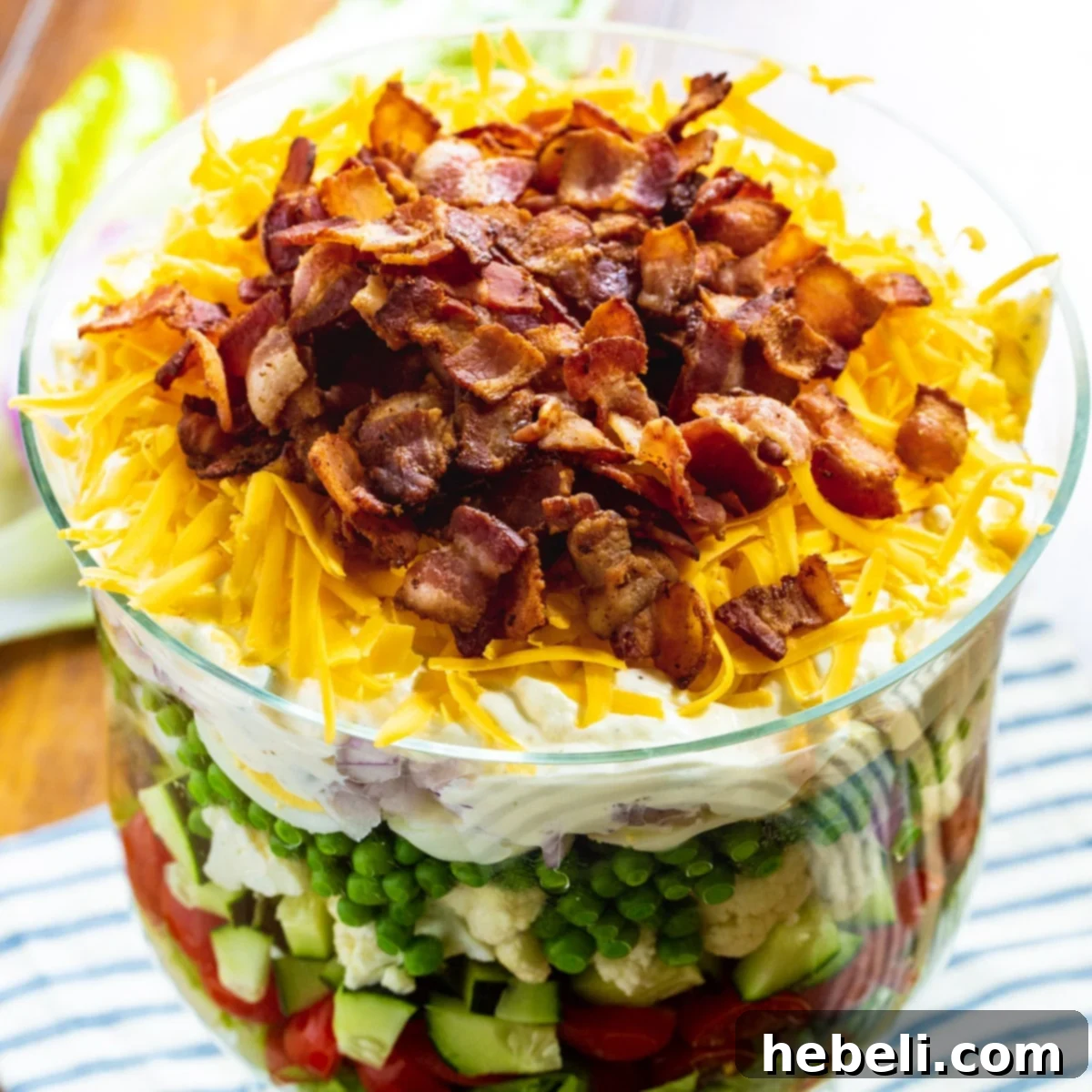 Classic Seven-Layer Salad in a clear trifle dish, showcasing distinct layers.