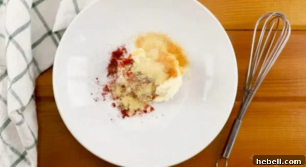 A bowl containing the mayonnaise mixture, seasoned with paprika, garlic powder, and seasoned salt