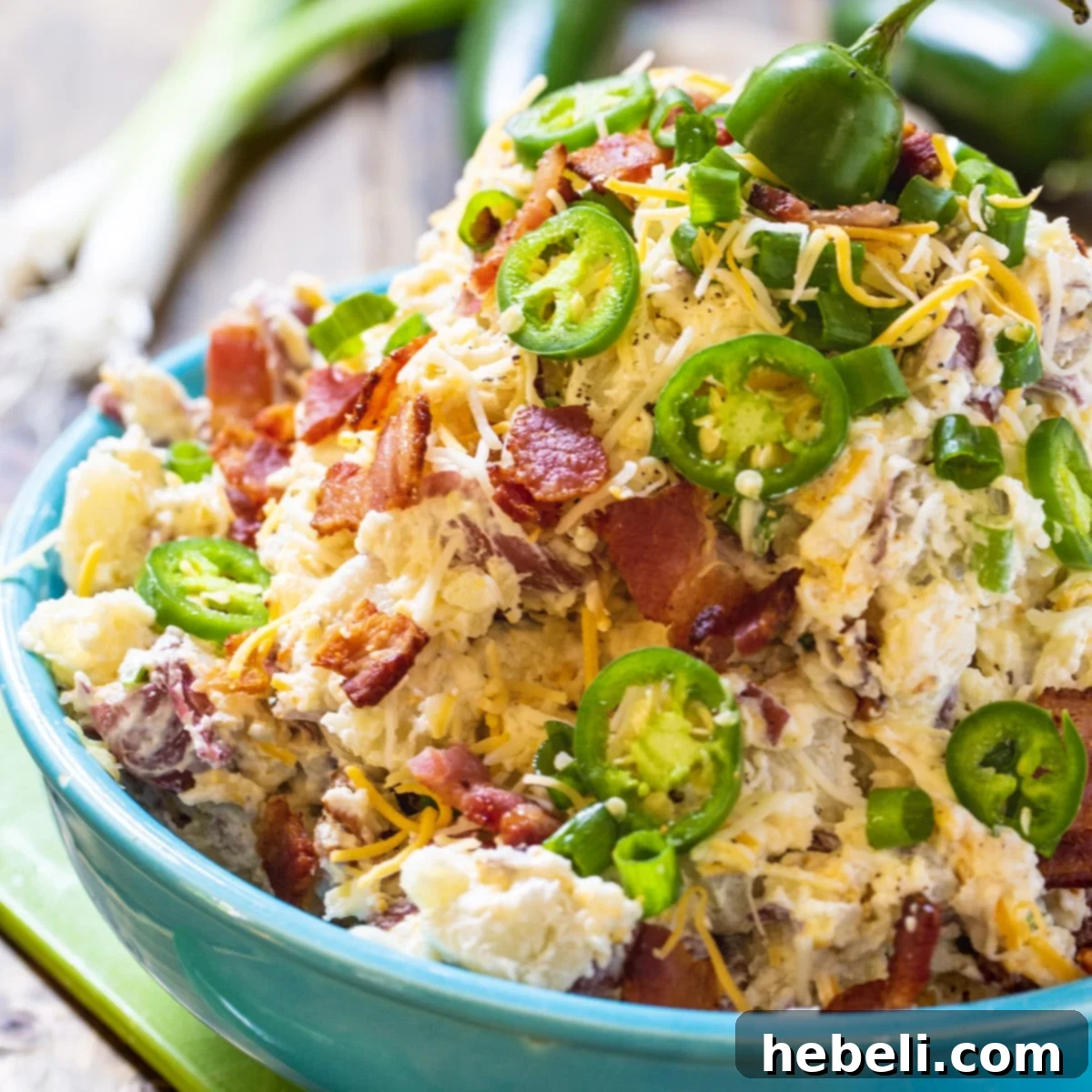 Creamy Jalapeno Popper Potato Salad in a vibrant blue serving bowl, garnished with fresh jalapeno slices and crumbled bacon, ready for serving.