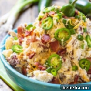 A vibrant and creamy Jalapeno Popper Potato Salad in a blue serving bowl, garnished and ready to be enjoyed as a perfect side dish.