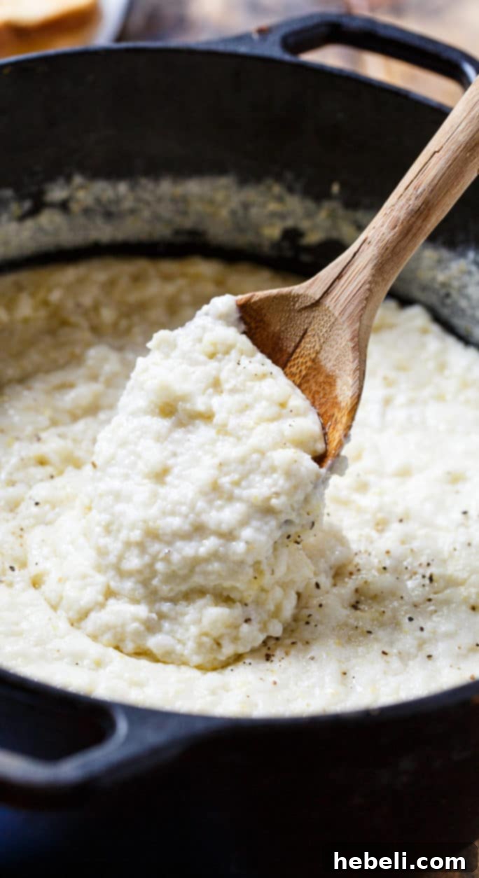 A wide shot showing a pot of creamy grits simmering on the stove, highlighting the thick, luscious texture and the rich color.