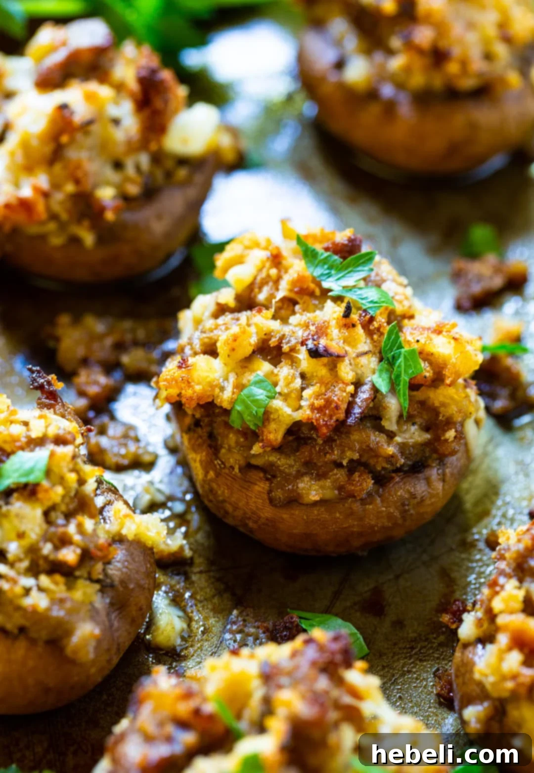 Batch of sausage stuffed mushrooms baking on a sheet pan, golden and delicious.