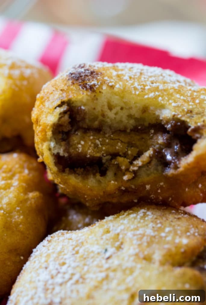 Golden-Fried Peanut Butter Delights 6 A hand holding a freshly deep-fried peanut butter cup, showing the melted chocolate and peanut butter inside.