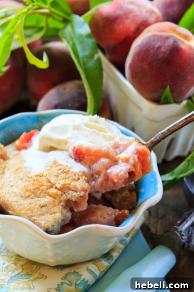 Warm Easy Southern Peach Cobbler topped with a scoop of vanilla ice cream