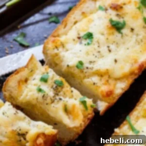 Ooey Gooey Garlic Bread 5 Close-up of a baked loaf of cheesy garlic bread, ready to be sliced.