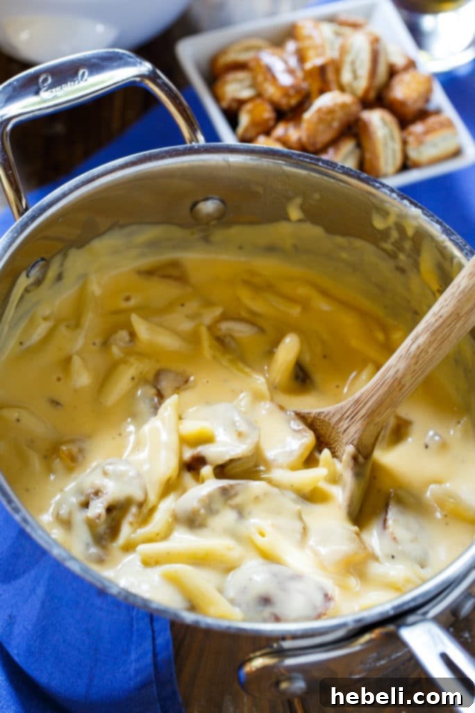 Close-up shot of Bratwurst Mac and Cheese with visible slices of grilled bratwurst and melted cheese, highlighting its creamy texture.