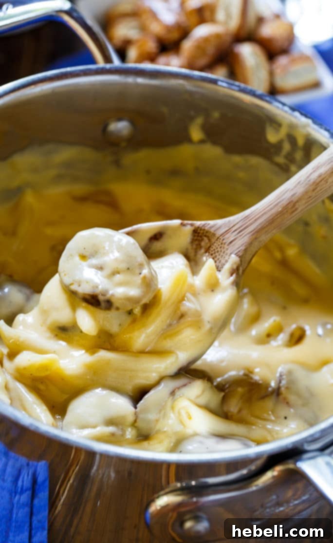 Overhead shot of Bratwurst Mac and Cheese in a bowl, with a fork digging in, emphasizing its appeal.