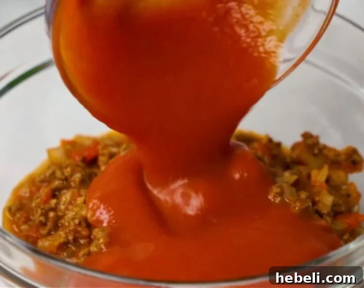 Lasagna Bell Pepper Bake 8 Adding tomato sauce to leftover ground beef mixture in the baking dish.