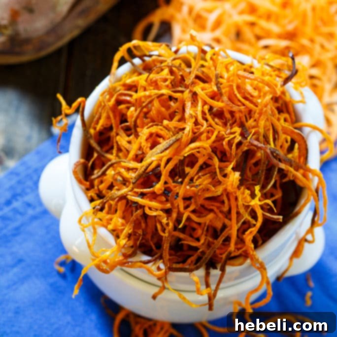Thin and crispy baked sweet potato straws on a baking sheet, ready to eat