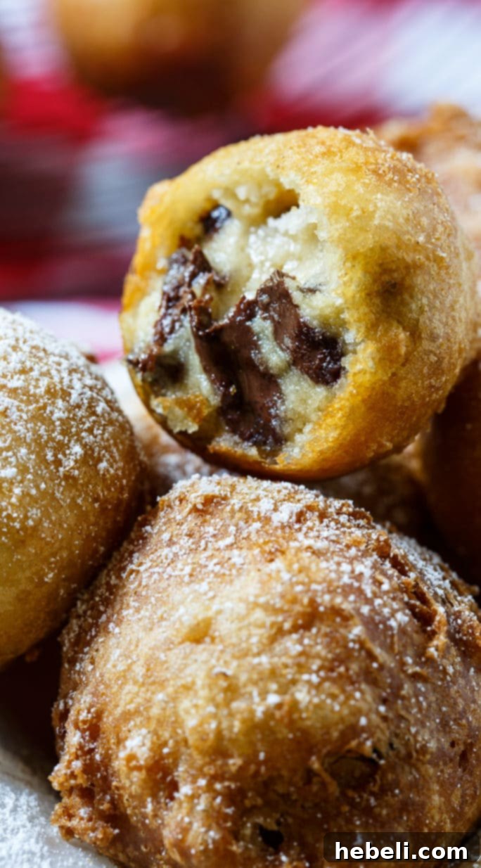 Frozen cookie dough balls neatly arranged on a parchment-lined tray, ready to be battered and fried