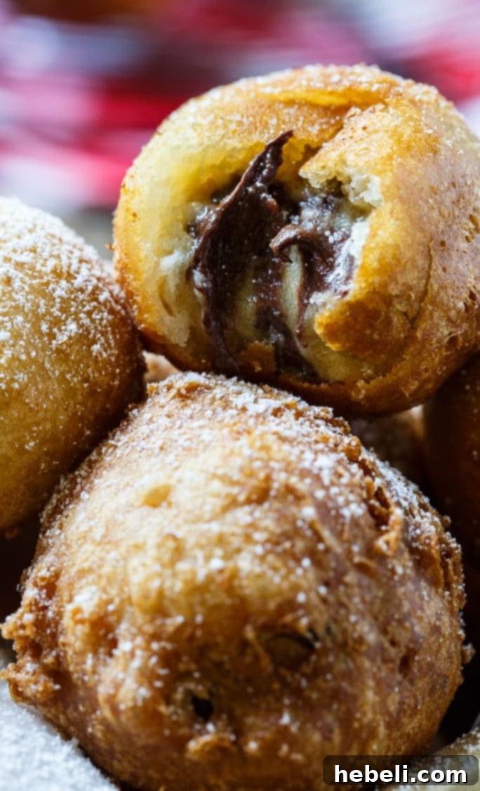 A close-up of a single Deep-Fried Cookie Dough ball, perfectly golden and dusted with powdered sugar, ready for a bite