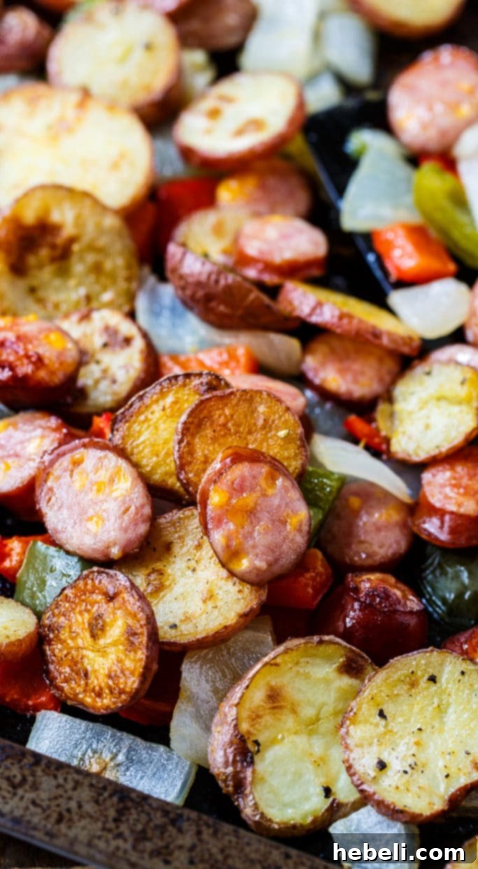 Raw ingredients, sliced potatoes, sausage, and vegetables, ready for Oven-Roasted Sausage and Potatoes preparation.