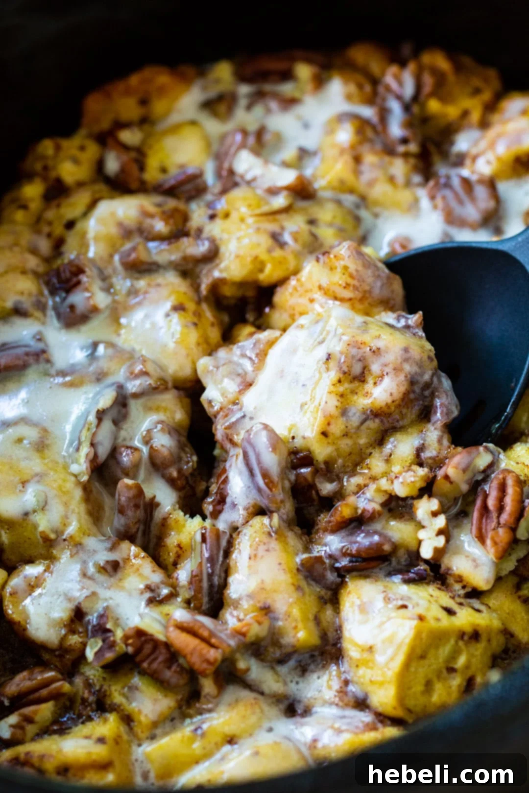 A serving of Crock Pot Cinnamon Roll Casserole with melted icing and visible gooey center.