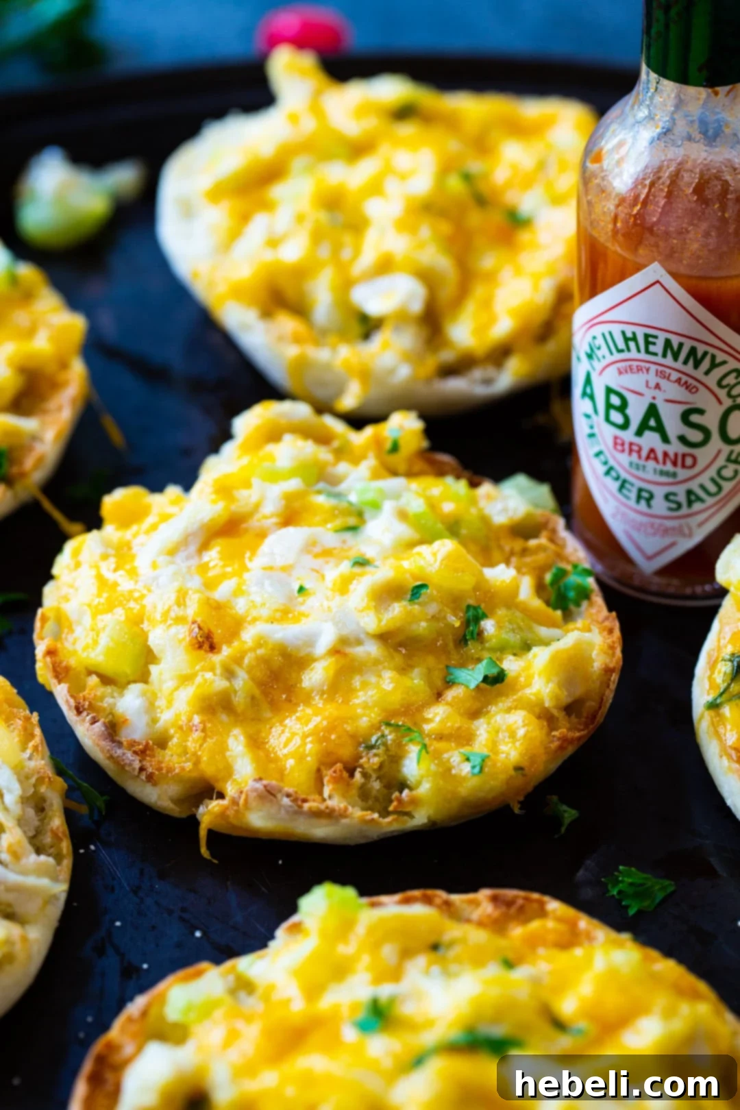 Sensational Crab Melts 5 Freshly prepared Crab Melts ready to be served, accompanied by a classic bottle of TABASCO Sauce on a baking sheet.