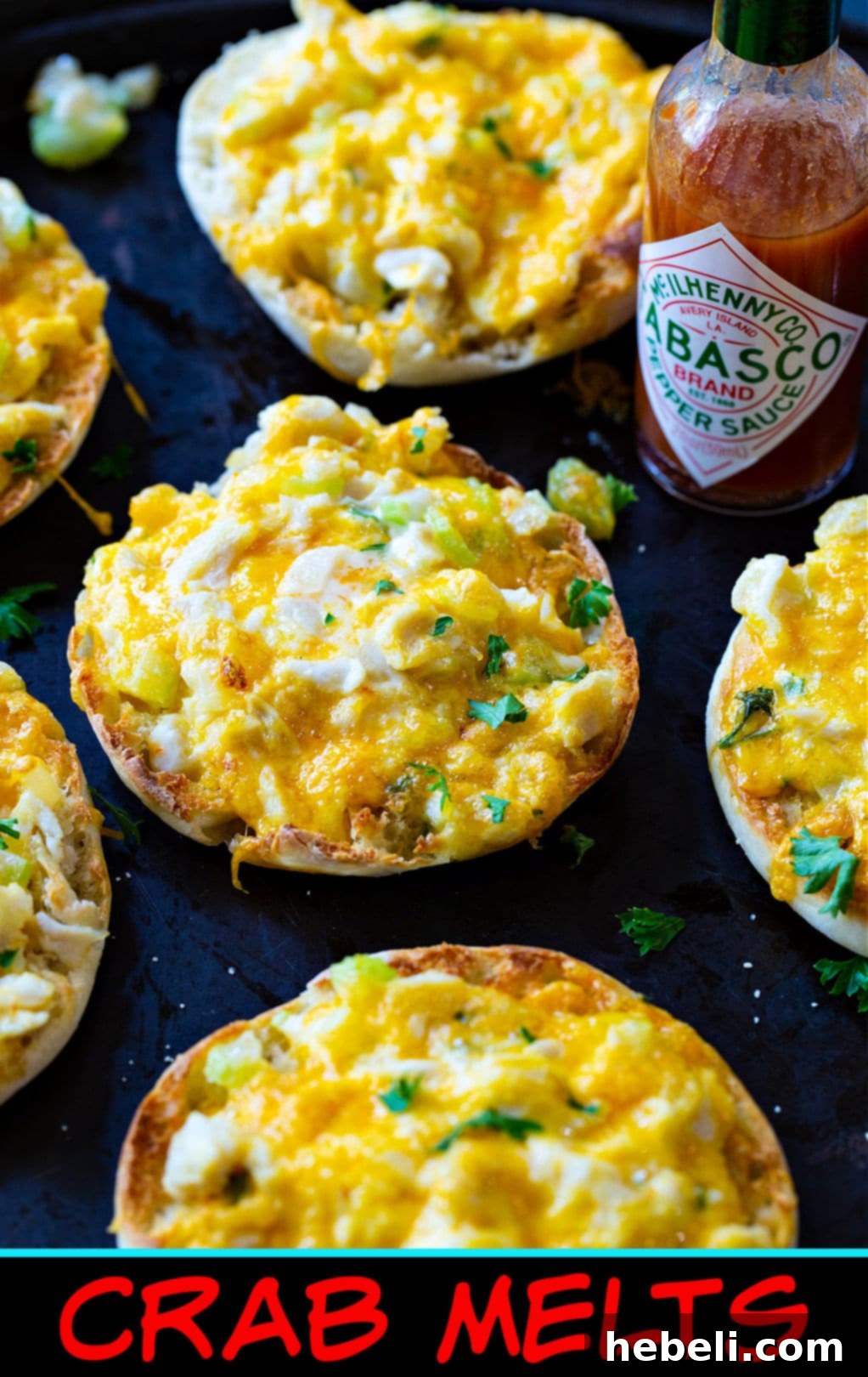 Sensational Crab Melts 7 A close-up shot of a finished Crab Melt, showcasing the gooey melted cheese, visible chunks of seasoned crab meat, and fresh parsley garnish on a toasted English muffin.