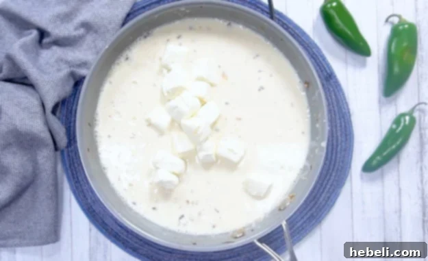 Kickin' Jalapeno Popper Chicken Bake 6 Adding cream cheese to the sauce and stirring until it melts into a smooth, creamy base.