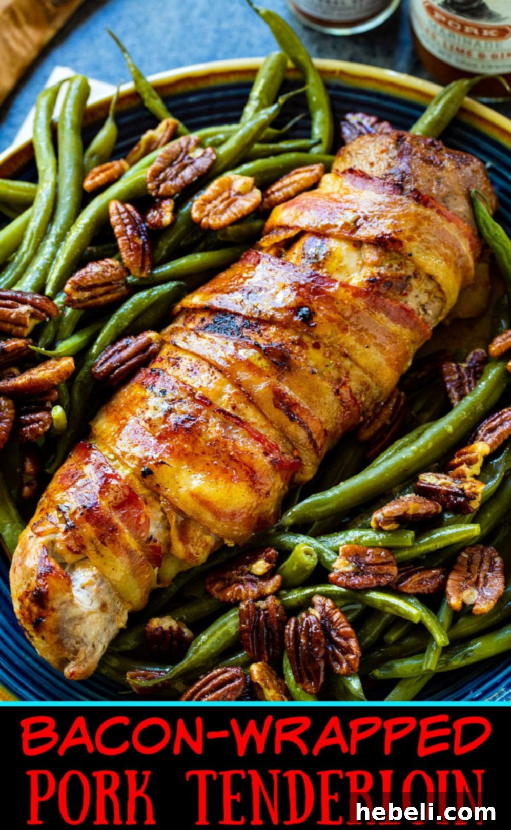 A delicious plate featuring sliced Bacon-Wrapped Pork Tenderloin, perfectly seared and served with a generous portion of green beans adorned with pecan vinaigrette.