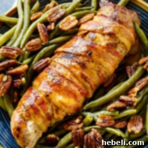 Close-up of a beautifully cooked Bacon-Wrapped Pork Tenderloin, showcasing its crispy bacon exterior and tender interior.