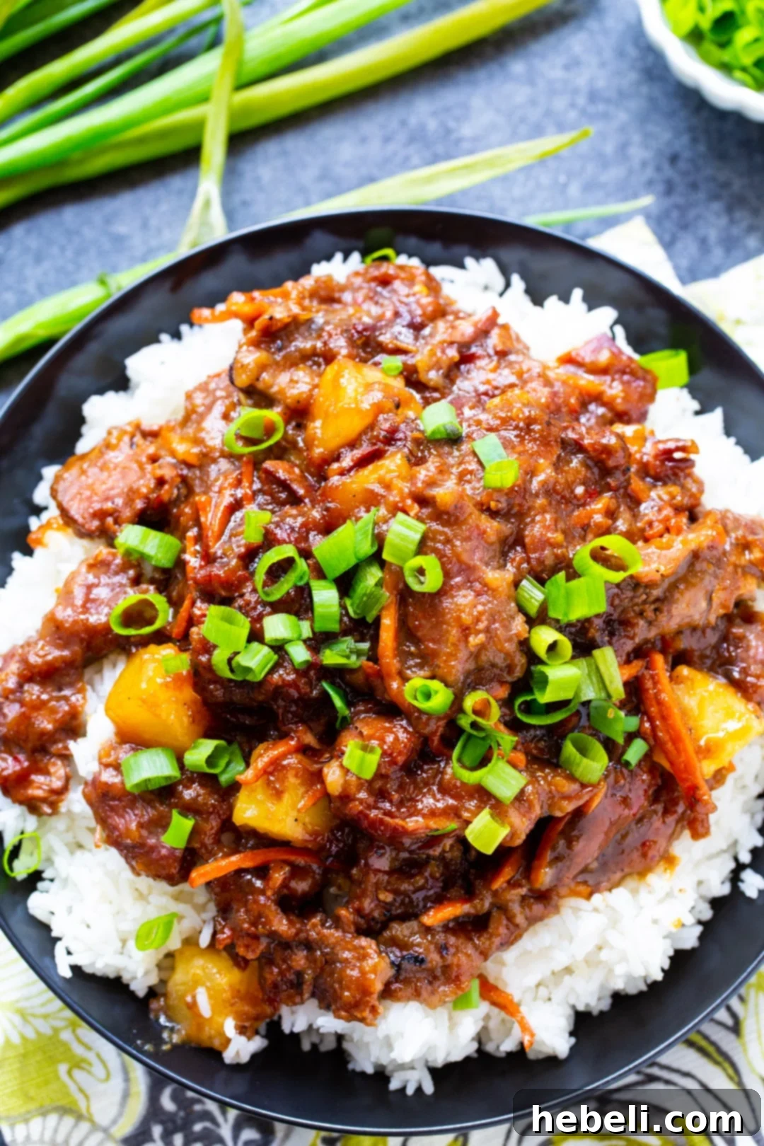 A close-up shot of a serving of Slow Cooker Spicy Mongolian Beef with Pineapple, highlighting the rich sauce, tender beef, and vibrant pineapple chunks.