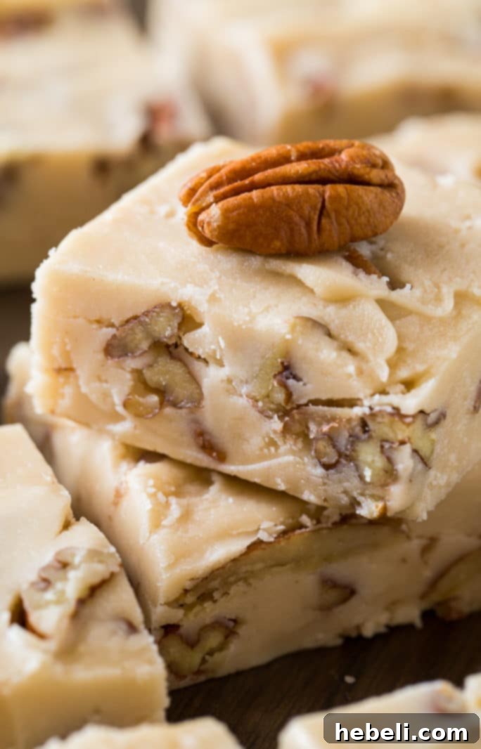 Many squares of Butter Pecan Fudge arranged on a rustic wooden board, ready to serve
