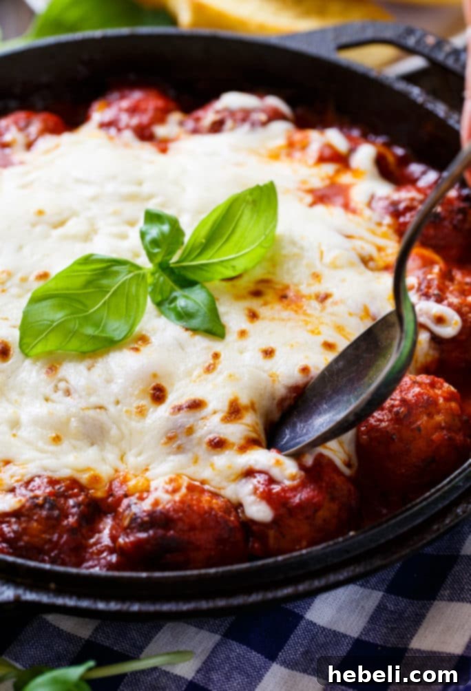 Cheesy Meatballs simmering in rich Marinara Sauce, ready for cheese.